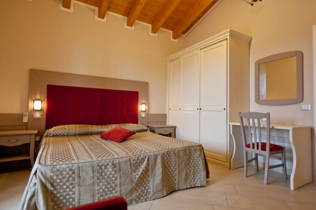 A bedroom with a bed, a desk, a chair, and a wardrobe.