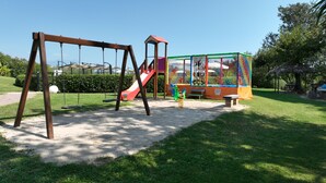 A playground with swings, a slide, and a climbing structure. - Gardahill (Soiano del Lago)