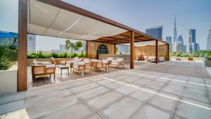 An outdoor seating area with a view of a city skyline, including a prominent skyscraper. - Modern Studio w Balcony in Business Bay (Dubai)