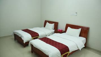 Twee enkele bedden met houten hoofdborden, wit beddengoed en rode decoratieve randen.