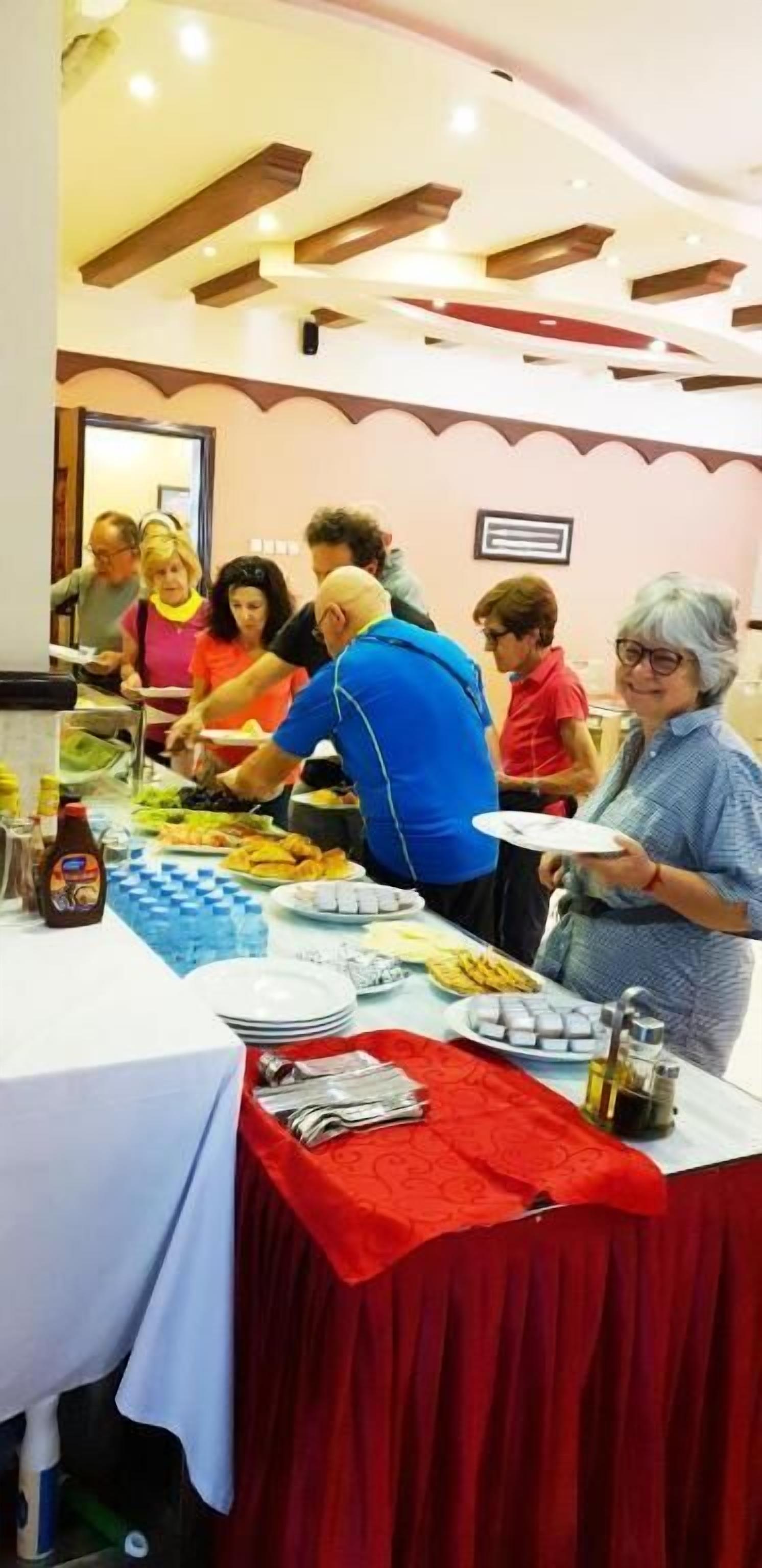 Un buffet est installé sur une table, avec une variété de plats et de boissons. Les convives peuvent se servir eux-mêmes ou être servis par le personnel.