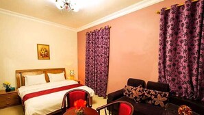 A hotel room with a bed, a sofa, a small table, and a chair. - Bahla Hotel Apartment  (Bahla)