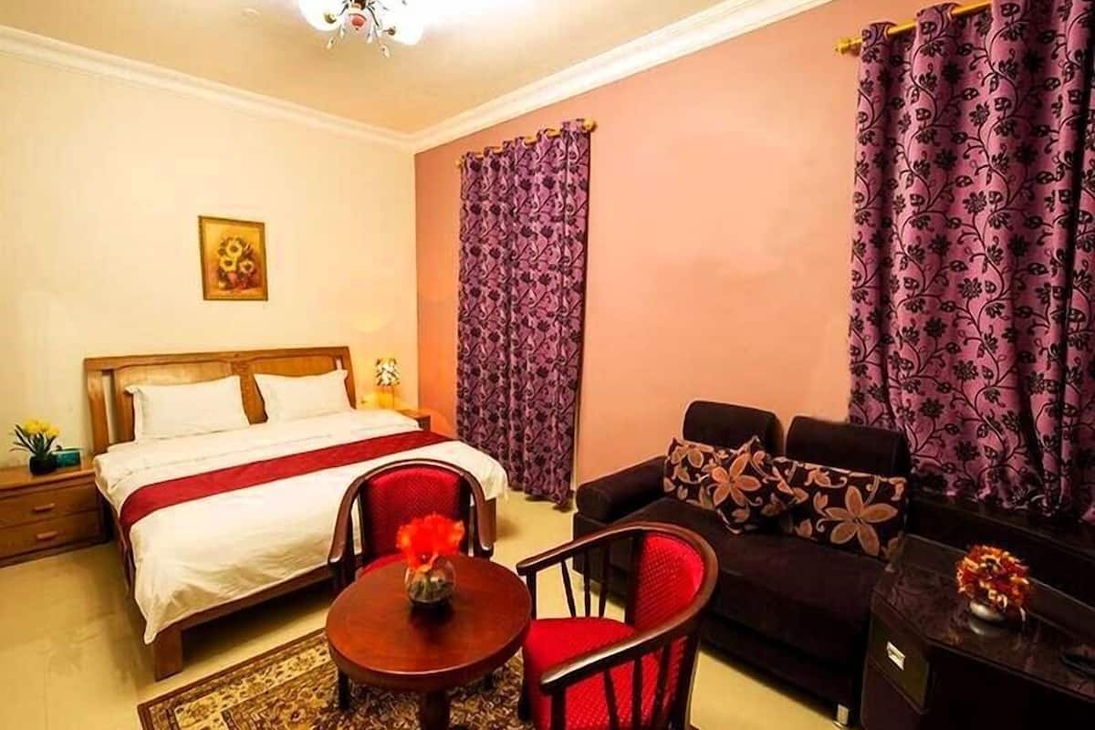 A hotel room with a bed, a sofa, a small table, and a chair.