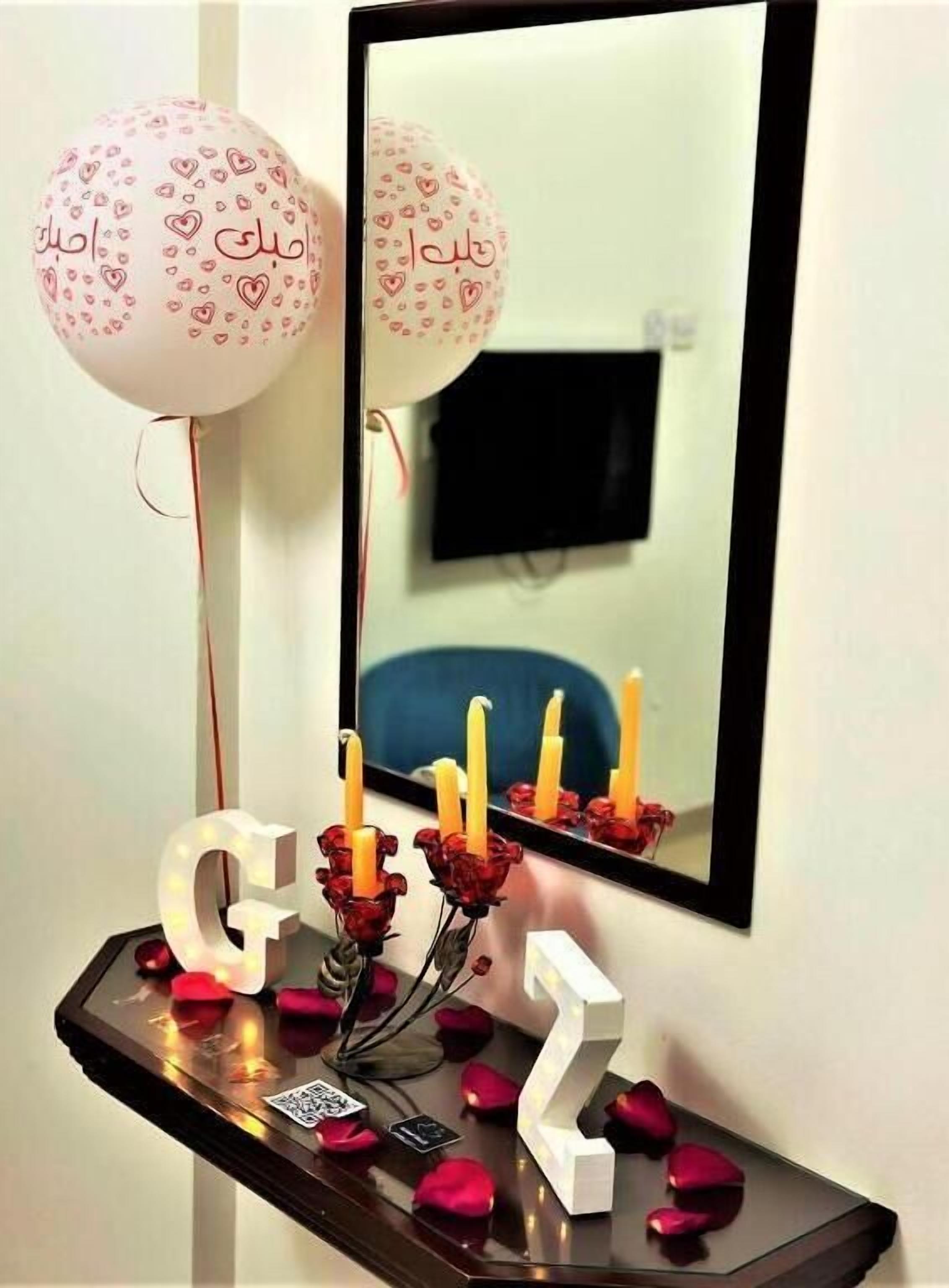 A room with a mirror, a table with candles, and balloons.