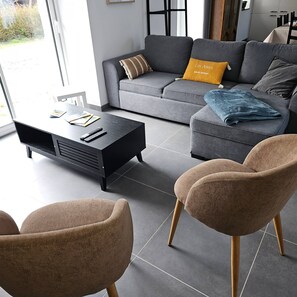 A modern living room with a grey sofa, a coffee table, and two brown chairs.