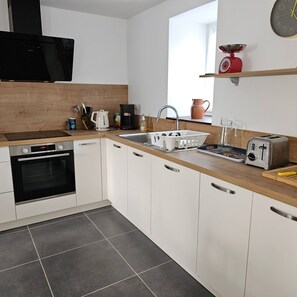 Una cocina moderna con armarios blancos, encimera de madera, horno empotrado, fregadero, cafetera y tostadora.
