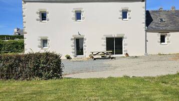 Une maison à deux étages avec une allée en gravier et un banc en bois devant.