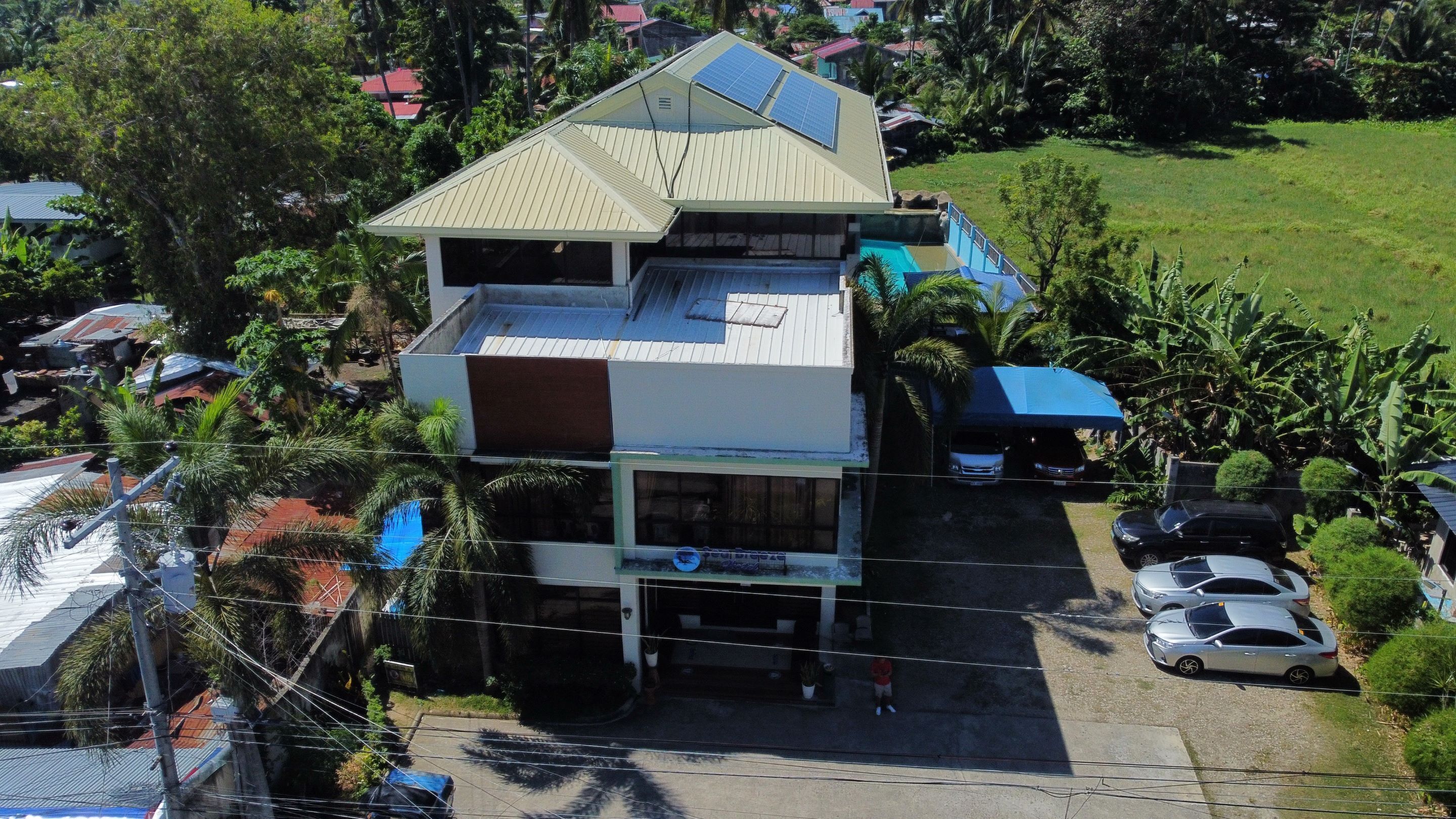Un edificio de varios pisos con techo plano, paneles solares y zona de estacionamiento cubierta.