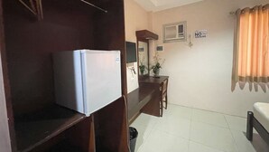 A compact room with a white refrigerator, a wooden cabinet, a small table with a mirror, and a sign indicating no smoking. - Argao Seabreeze Hotel powered by Cocotel (Argao)