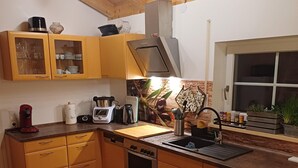 Eine kompakte Küche mit Holdekor-Schränken, einem Einbauofen, einer Spüle und einem Essbereich mit Tisch und Stuhl.