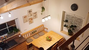 Ein Holztisch mit Obstschale, einer Bank und einer Küchenzeile mit Spüle und Schränken.