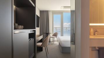 Habitación de hotel con cama, escritorio, silla, una mesita y balcón con vistas.