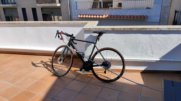 A bicycle parked on a tiled balcony with a white wall and a tiled roof in the background. - Àtic Cèntric a Eixample-barri Vell (Girona)