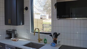 A modern kitchen with a large window, a coffee maker, and a sink.