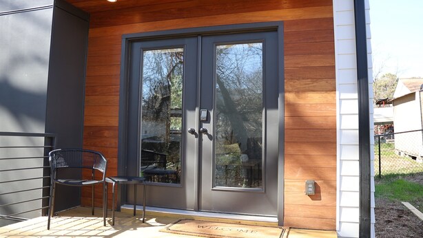 A modern entrance with a double door, a bench, and a welcome mat.
