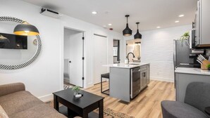 Een moderne keuken met een centraal eiland, een zithoek met een bank en een woonkamer met een salontafel.