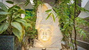 A Buddha statue with a light source, surrounded by plants and rocks. - Natural Lake View Hotel (Udaipur)