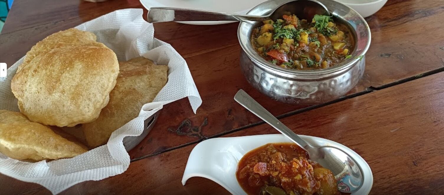 A meal consisting of fried bread, a stew, and a side dish on a wooden table.