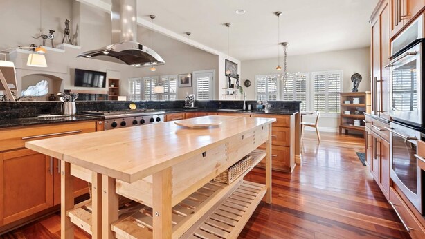 A spacious kitchen with a large island, wooden cabinets, and a stainless steel range hood. - Scenic Serenity in Immaculate Custom Home with Breathtaking Mountain Views & Cozy Fireplace (Boise)