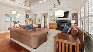 A spacious living room with a large brown sectional sofa, a wooden coffee table, and a fireplace. - Scenic Serenity in Immaculate Custom Home with Breathtaking Mountain Views & Cozy Fireplace (Boise)