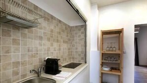 A kitchen with a sink, a coffee maker, and a tiled backsplash. - Tembo House - Pantano 2 (Catania)