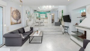 A modern living room with a grey sofa, a coffee table, and a fireplace. - Beachfront " Villa Io " (Katerini)