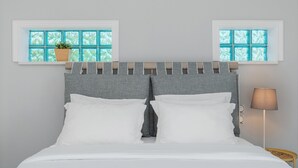 A neatly made bed with white linens, a grey headboard, and two windows with a view of greenery. - Beachfront " Villa Io " (Katerini)