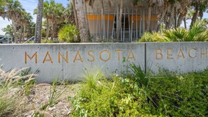 Un panneau en béton sur lequel est inscrit en grandes lettres « MANASOTA BEACH ».