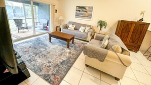 Un salon comprenant un canapé, une table basse et offrant une vue sur l’extérieur grâce à de grandes portes-fenêtres coulissantes.
