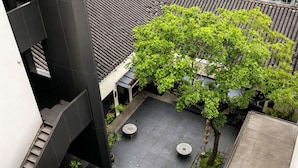 A courtyard with a tree, two round tables, and a tiled floor. - Jiangnan House Guanqianjie  (Suzhou)