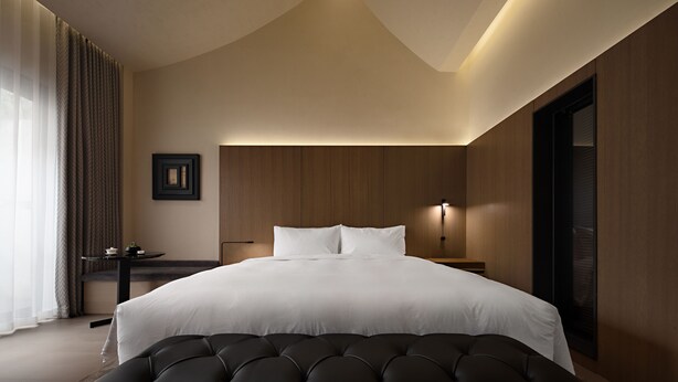 A modern hotel room with a large bed, a bedside table, a lamp, and a view of the outdoors. - Jiangnan House Guanqianjie  (Suzhou)
