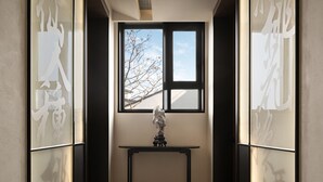 A hallway with frosted glass panels featuring calligraphy, a window with a view of bare trees, and a small table with a sculpture. - Jiangnan House Guanqianjie  (Suzhou)