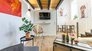 A modern living room with a sofa, a colorful chair, a glass coffee table, and a plant.