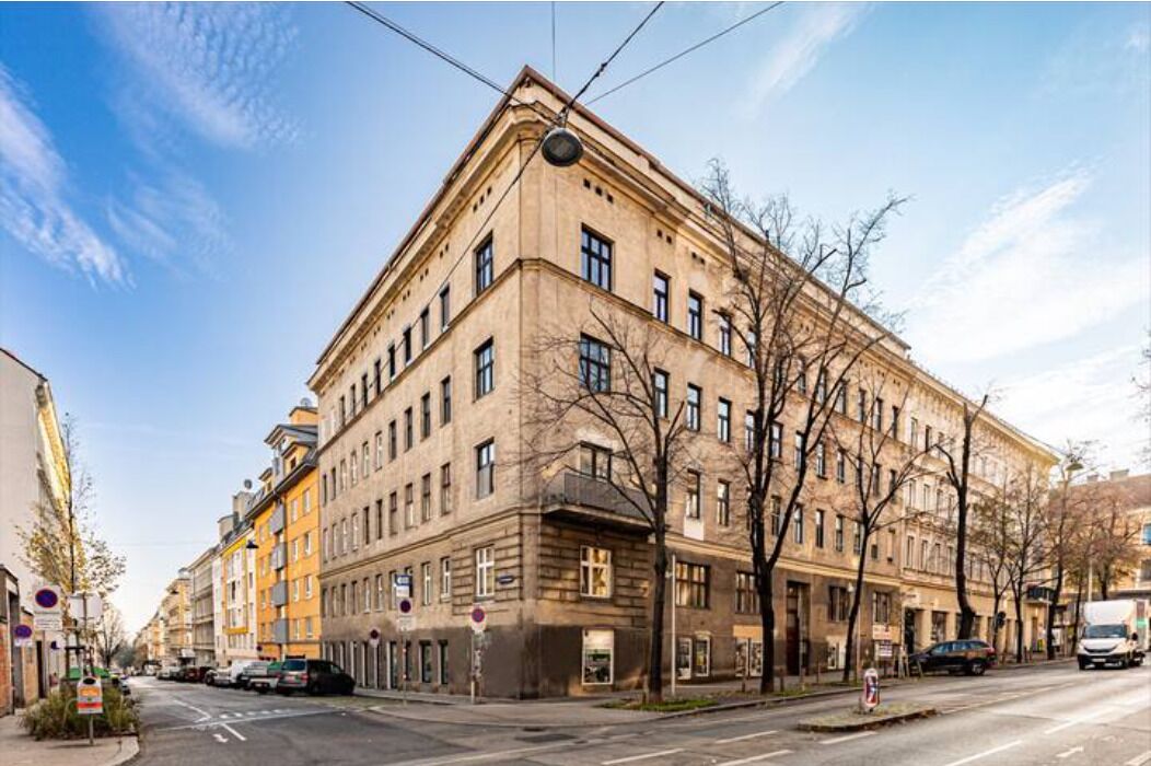 En byggnad med flera våningar i klassisk arkitektonisk stil, med en framträdande entré i hörnet och stora fönster.