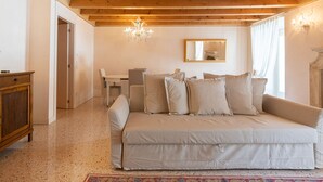 A cozy room with a beige sofa, a wooden cabinet, a chandelier, and a mirror on the wall. - Corte Spagnola - piano primo (Verona)