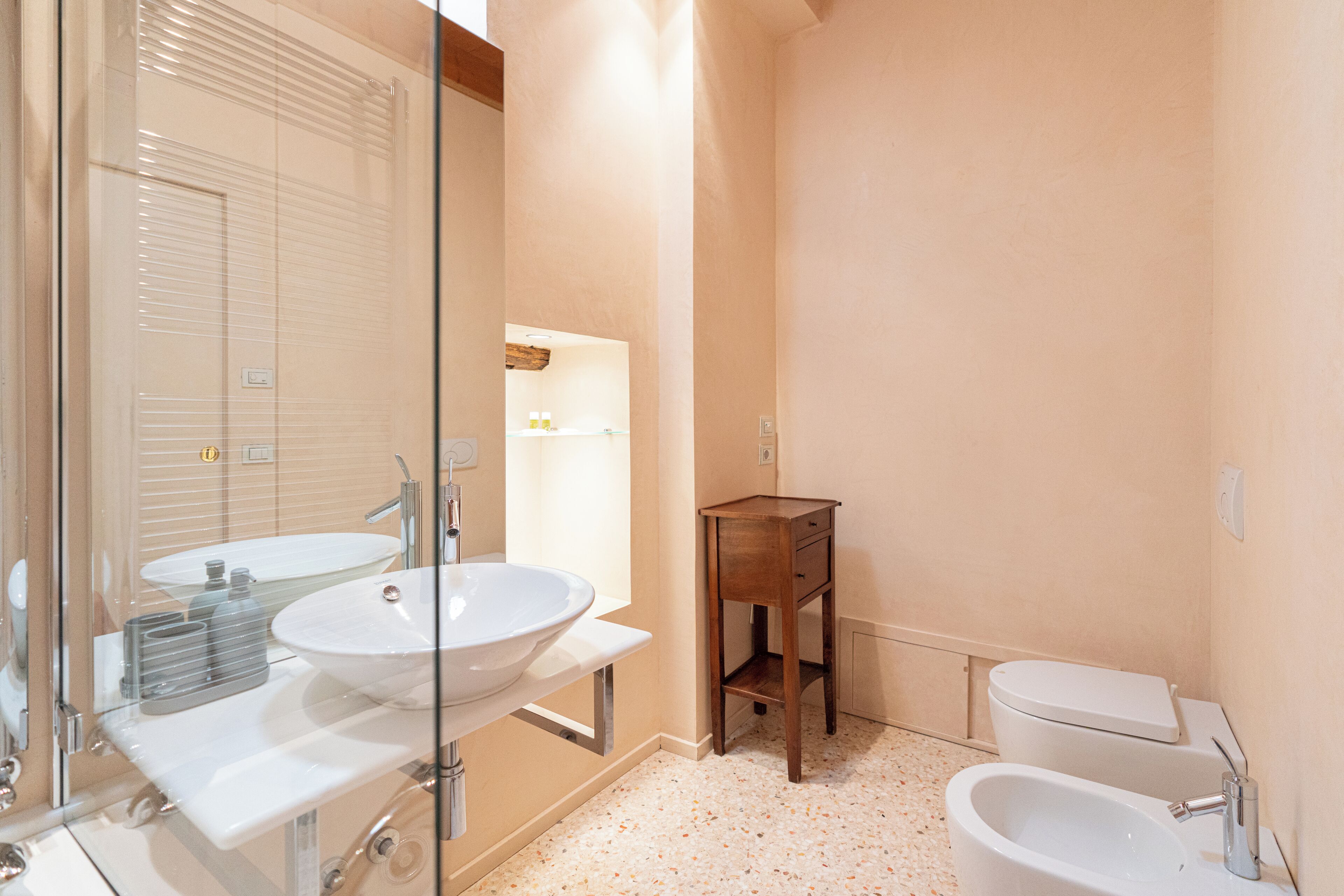 A bathroom with two sinks, a toilet, and a small wooden cabinet.