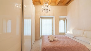 A bedroom with a large bed, a chandelier, and a view of the outside. - Corte Spagnola - piano primo (Verona)