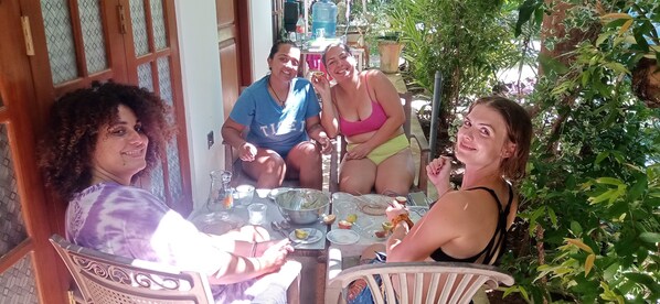 A group of people seated at an outdoor table with various dishes and drinks, surrounded by greenery. - Terrific 3-bedroom resort with WiFi, AC in Mirissa (Mirissa)