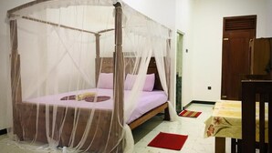 Een kamer met een hemelbed, een houten garderobe en een klein tafeltje met tafelkleed.