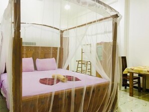 A bed with a canopy, a wooden headboard, and a bedside table with a lamp. - Terrific 3-bedroom resort with WiFi, AC in Mirissa (Mirissa)