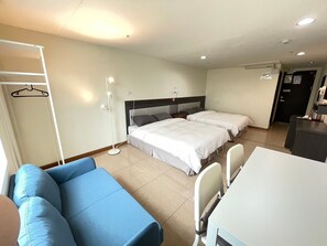 Une chambre d’hôtel avec deux lits, un bureau, une chaise, une armoire et une lampe sur pied.