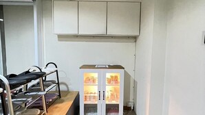 Um corredor com um porta-sapatos, um armário com portas de vidro e uma abertura no teto.