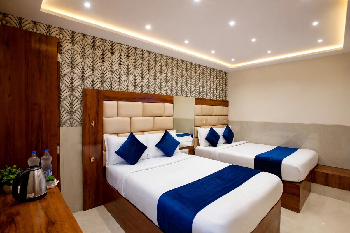 Habitación de hotel con dos camas, un armario de madera, un hervidor y un papel tapiz estampado.