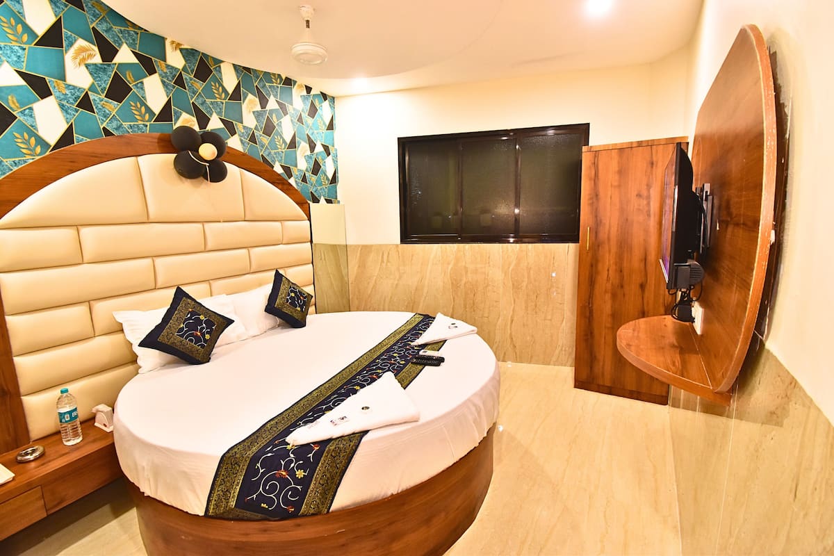 Ein Bett mit runder Form und Holz-Kopfschild, ein Holzschrank, ein an der Wand montierter Fernseher und eine Wand mit Muster.