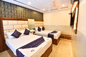 Une chambre d’hôtel avec deux lits, un mur décoré de motifs et un ventilateur de plafond.