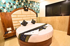 Habitación de hotel con una cama redonda, cabecera de madera, pared con diseño y una ventana.