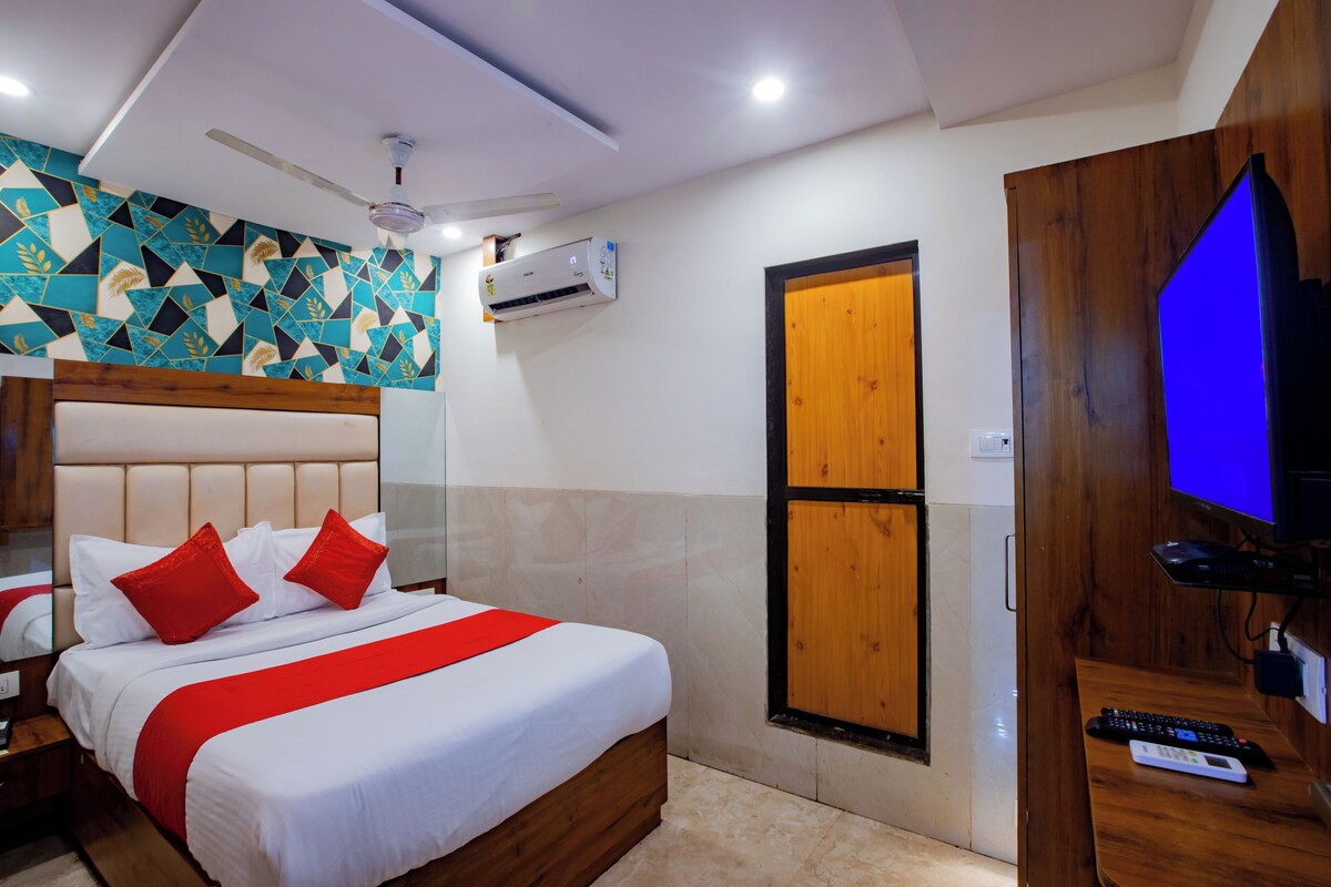 Una habitación de hotel con una cama, un televisor, una puerta de madera y un equipo de aire acondicionado.