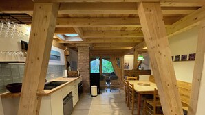 A kitchen with wooden beams, a dining area with a table and chairs, and a view of the outdoors. - Spacious, cozy attic apartment with mountain views on 1.5 floors (Berg)
