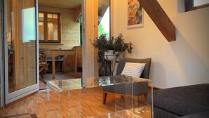 A modern living room with a glass coffee table, a gray sofa, and a wooden floor. - Spacious, cozy attic apartment with mountain views on 1.5 floors (Berg)