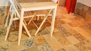 Uma sala de jantar com uma mesa posta para quatro pessoas, um espelho na parede e uma porta vermelha que dá para outro aposento.